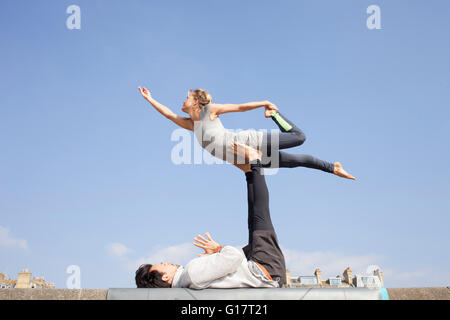 Mann und Frau üben akrobatische Yoga an Wand