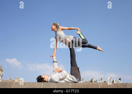 Mann und Frau üben akrobatische Yoga an Wand Stockfoto