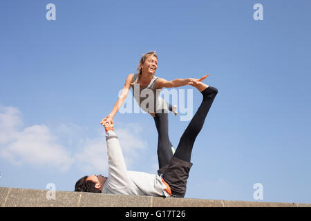 Mann und Frau an Wand akrobatische Yoga zu praktizieren Stockfoto