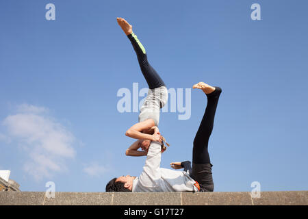 Mann und Frau üben akrobatische Yoga gegen blauen Himmel Stockfoto