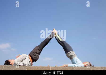 Mann und Frau üben akrobatische Yoga gegen blauen Himmel Stockfoto