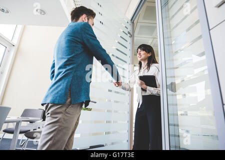 Junge Geschäftsfrau und Client Händeschütteln im Büro Stockfoto