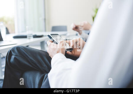 Schuss der Geschäftsfrau SMS auf Smartphone im Büro beschnitten Stockfoto