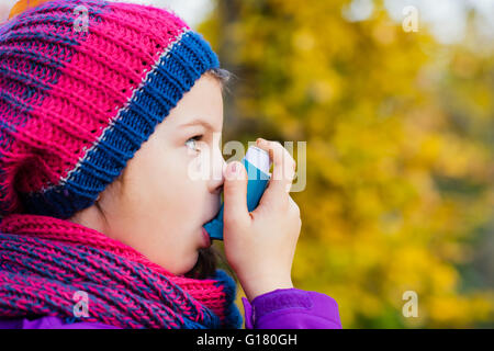 Mädchen benutzen Inhalator an einem Herbsttag - zur Behandlung von Asthma-Anfall. Inhalation Behandlung von Erkrankungen der Atemwege. Stockfoto