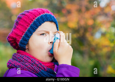 Mädchen benutzen Inhalator an einem Herbsttag - zur Behandlung von Asthma-Anfall. Inhalation Behandlung von Erkrankungen der Atemwege. Stockfoto