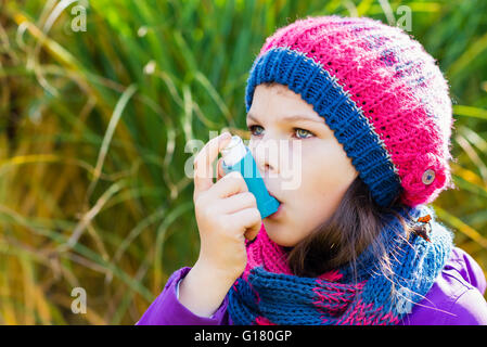 Mädchen benutzen Inhalator an einem Herbsttag - zur Behandlung von Asthma-Anfall. Inhalation Behandlung von Erkrankungen der Atemwege. Stockfoto