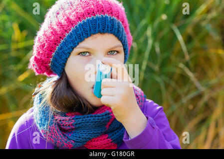 Mädchen benutzen Inhalator an einem Herbsttag - zur Behandlung von Asthma-Anfall. Inhalation Behandlung von Erkrankungen der Atemwege. Stockfoto