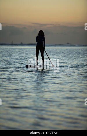 Gemächlich paddeln Frau Stand-up Board am Ala Moana Beach Park bei Sonnenauf- oder Sonnenuntergang. Stockfoto
