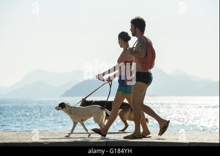 RIO DE JANEIRO - 3. April 2016: Brasilianisches Ehepaar ihre Hunde an einem hellen Morgen Blick auf der Copacabana-Promenade gehen. Stockfoto