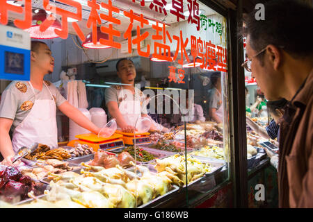 Kunde beobachtet Fleisch chinesischer Metzger auf einem Indoor-Markt in Nanjing, China Stockfoto