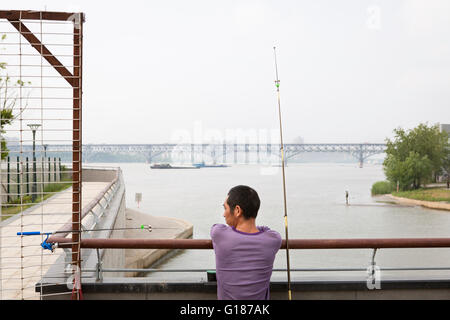 Blick auf den Yangtze-Fluss und Brücke in Nanjing mit einem entspannten Fisher Mann im Vordergrund mit einem Blick Stockfoto