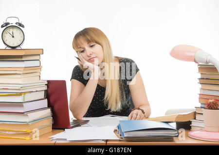 Müde von der Suche auf dem Laptop an der Rezeption in der Bibliothek Student vollgestopft mit Stapeln von Büchern Stockfoto