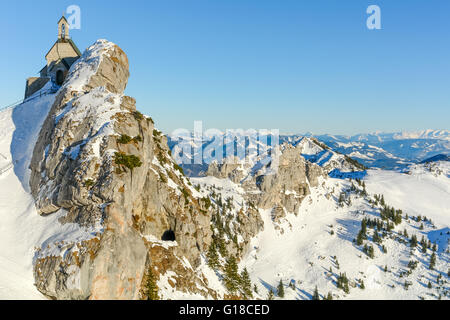 Alpine Kapelle thront auf einem verschneiten Berg. Stockfoto