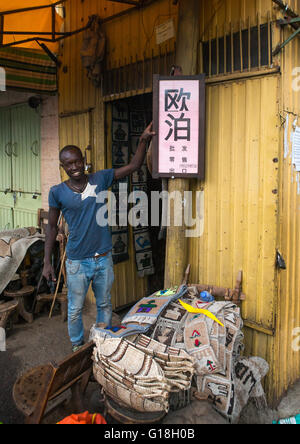 Äthiopischen Mann vor einem Plakat in der chinesischen Sprache Opales, Addis Abeba Region, Addis Ababa, Äthiopien zu verkaufen Stockfoto