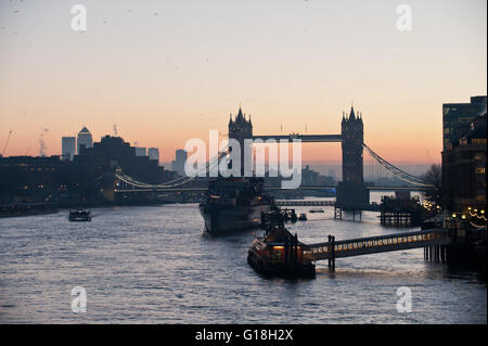 Sonnenaufgang auf der Themse in Richtung Tower Bridge mit HMS Belfast und Canary Wharf im Hintergrund Stockfoto