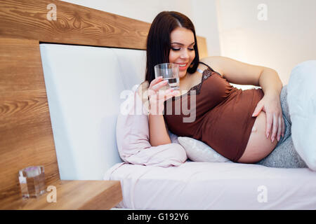 Schöne schwangere Frau Trinkwasser zu bleiben hydratisiert Stockfoto