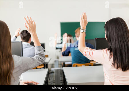 Junge Studenten, die Hände in einem Klassenzimmer zeigen, dass sie bereit sind Stockfoto