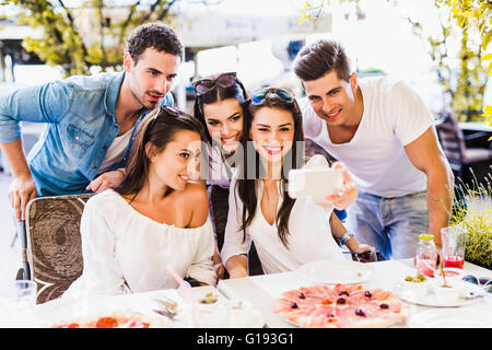 Gruppe von schönen Jugendlichen in einem Restaurant sitzen und dabei das Lächeln auf den Lippen eine selfie Stockfoto