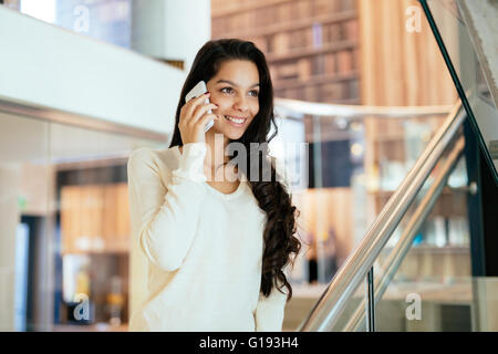 Geschäftsfrau mit Handy drinnen und lächelnd Stockfoto