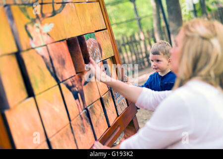 Schöne Mutter und ihr Sohn auf dem Spielplatz spielen Stockfoto