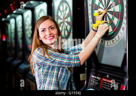 Junge schöne Frau in einem Club Dart spielen und Lächeln Stockfoto