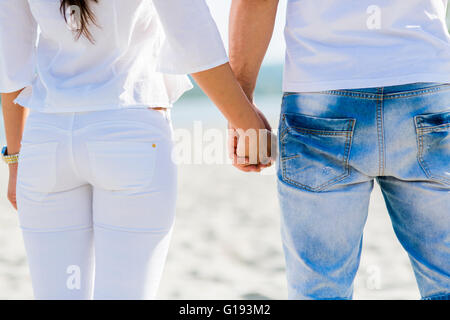 Romantisch zu zweit halten die Hände an einem Strand