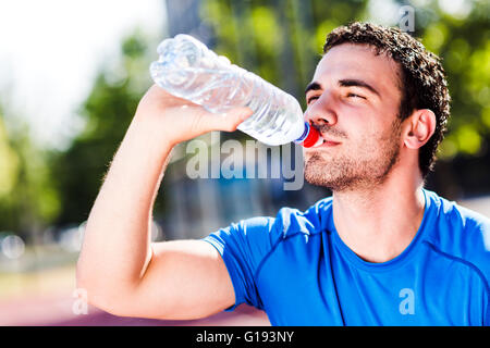 Schönen jungen sportlichen Mann Trinkwasser an einem heißen Sommertag an seinem Körper und Geist erfrischen Stockfoto