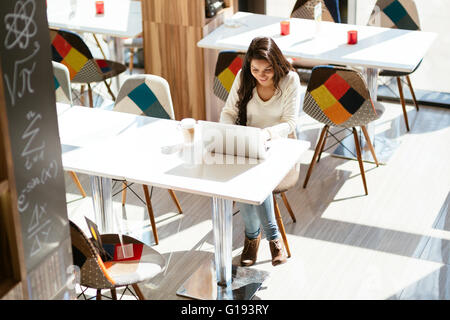 Schöne Brünette mit Laptop im café Stockfoto