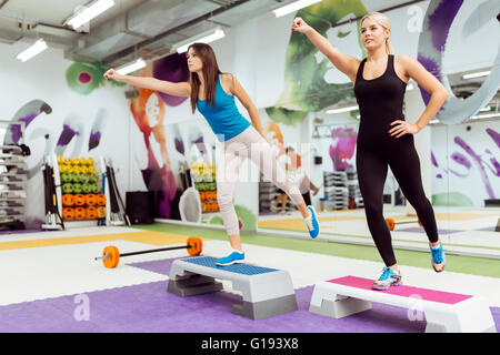 Schöne Frauen, die Aerobic im schönen Fitnessclub trainieren Stockfoto