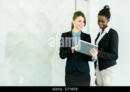 Zwei Geschäftsfrauen mit Blick auf eine Tablette und Diskussion der Ergebnisse mit einer Glas-Reflexion Stockfoto