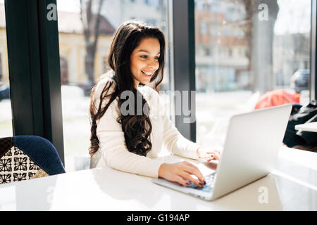 Schöne Brünette mit Laptop im café Stockfoto