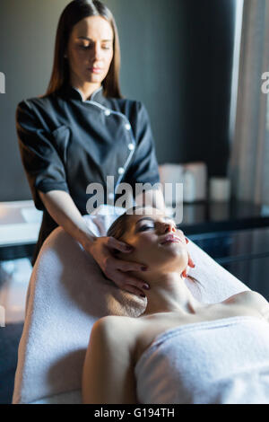 Behandlung von Gesicht, eine schöne, junge Frau auf der Massagebank liegen Masseur Stockfoto