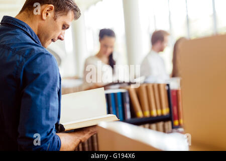 Gut aussehend Student liest ein Buch eine wunderschöne Bibliothek Stockfoto