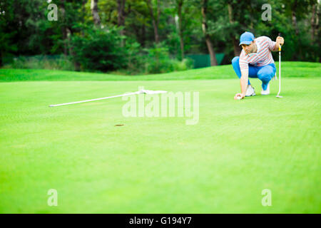 Golfspieler, die Kugel auf dem Putting-Green vor dem Anheben des Balls markieren Stockfoto