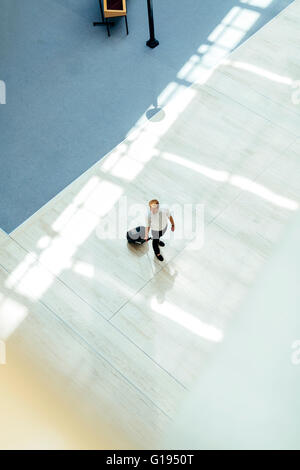 Gut aussehend Geschäft hält einen Wagen und zu Fuß in einem modernen Gebäude, die von oben gesehen Stockfoto