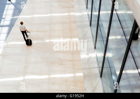 Gut aussehend Geschäft hält einen Wagen und zu Fuß in einem modernen Gebäude, die von oben gesehen Stockfoto