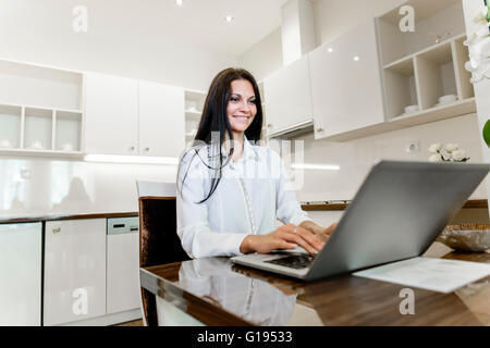 Schöne Brünette arbeiten auf einem Laptop in ihr schönes Zuhause Stockfoto