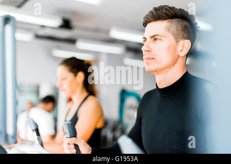 Gruppe von gesunden jungen Menschen mit Laufband und Crosstrainer im Fitness-Studio Stockfoto