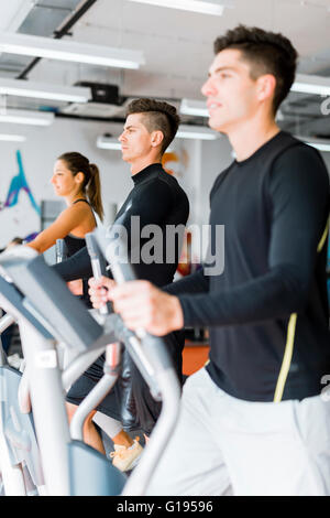 Junge gesunde Gruppe von Menschen, die Arbeiten auf eine elliptische Trainer in einem Fitnesscenter Stockfoto