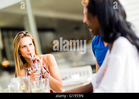 Schöne Frau trinken mit einem Strohhalm im Freien sitzen an einem Tisch Stockfoto
