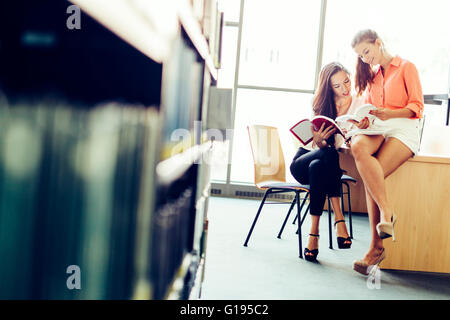 Zwei schöne Studenten studieren in der Bibliothek und Bücher zu lesen Stockfoto