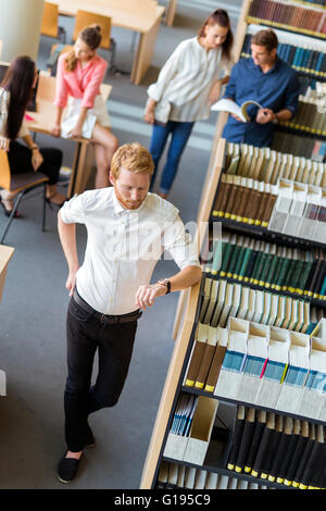 Gruppe von Jugendlichen, die Vorbereitung auf eine Exame in einer Bibliothek und haben nicht viel Zeit übrig. Termin Stockfoto