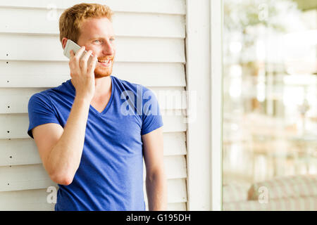 Glücklich roten Haaren hübscher Mann mit Handy und lächelnd an einem Sommertag Stockfoto