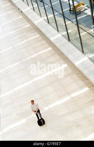 Gut aussehend Geschäft hält einen Wagen und zu Fuß in einem modernen Gebäude, die von oben gesehen Stockfoto