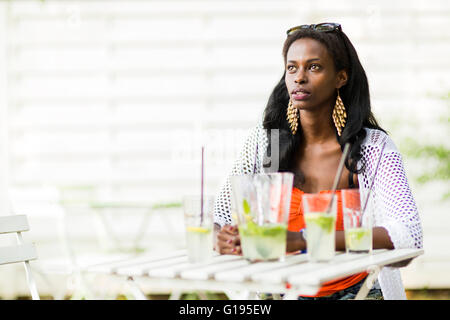 Schöne Frau sitzt an einem Tisch allein und wartet auf für Freunde Stockfoto