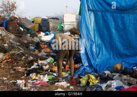 Ein Flüchtling sucht unter den Müll nach 1. Räumung von The Jungle. Flüchtling & Migrant Camp, Calais, Nordfrankreich Stockfoto