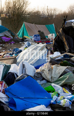 Ein einsamer Mann sitzt unter den Müll nach 1. Räumung. Der Dschungel Flüchtling & Migrant Camp, Calais, Nordfrankreich Stockfoto