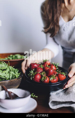 Eine Frau ist eine Schale mit Erdbeeren auf einem Tisch platzieren, immer bereit, Erdbeeren und Spinat Salat fotografiert zusammengestellt Stockfoto