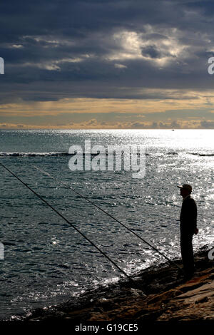 Costa Blanca Spanien Alicante Stadt Mann Angeln vom Felsen Playa del Postiguet Stockfoto