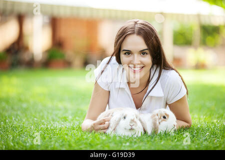 Junges Mädchen mit zwei Hauskaninchen in einem park Stockfoto